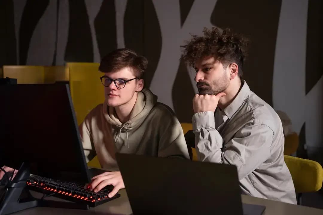 Two developers collaborating at their workstations in a modern office environment